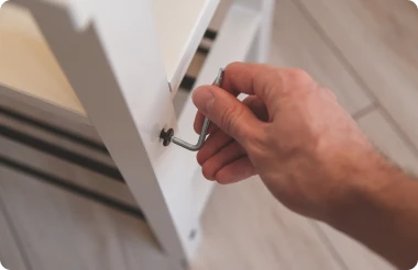 A person using an allen key to assemble furniture.