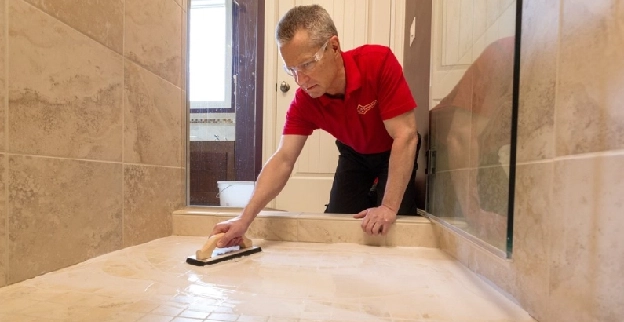 Mr. Handyman grouting bathroom shower tile floor.