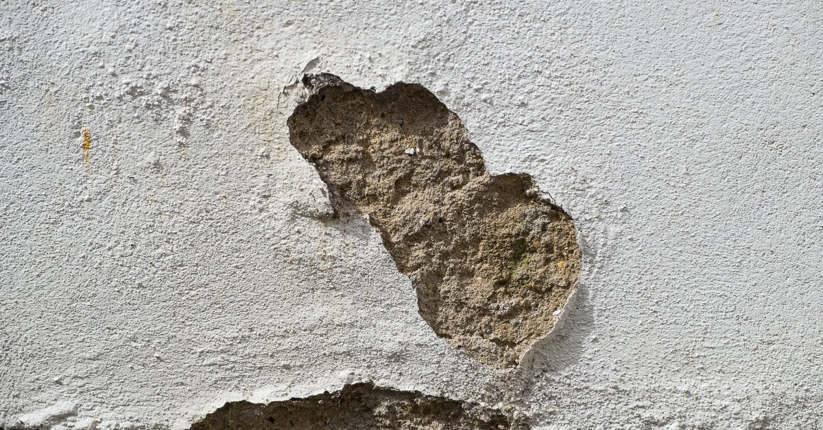 A close-up of damaged stucco on the exterior of a home in need of stucco repair services.