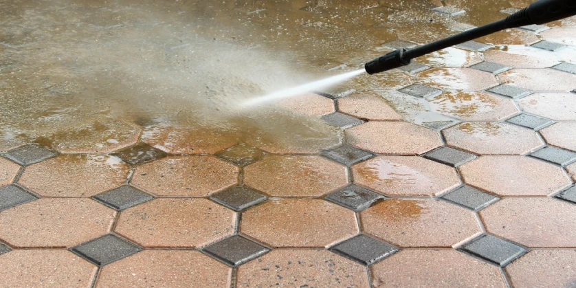 A close-up of a pressure washer nozzle as it sprays stone tiles with water during an appointment for a pressure washing service.