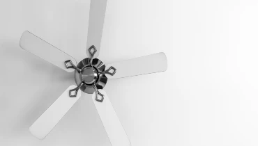 Ceiling fan with white blades hanging from a white residential ceiling after installation. 