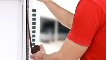 Handyman installing a rubber strip on the side of a window for window repair in wichita, ks