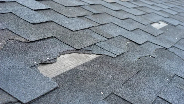 Residential roof with a section of damaged shingles that require roof repair services