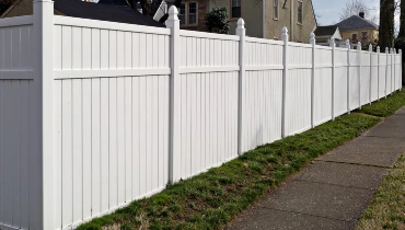 White vinyl fence that has been recently installed around the backyard of a house
