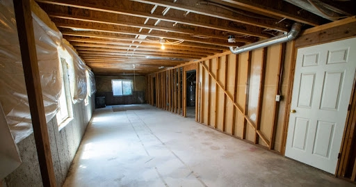 An unfinished basement with exposed frames that has been cleaned and prepped for a basement remodel.