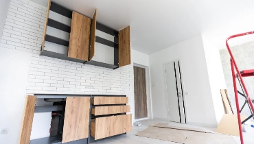 An in-progress kitchen remodel involving the installation of new cabinets, cupboards, and a new tile backsplash.