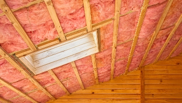 Pink attic insulation covering the ceiling of a residential attic space in Boulder.