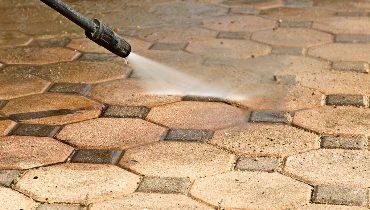 A close up image of the nozzle of a pressure washer as it sprays a jet of water at stone tiles during a pressure washing appointment.