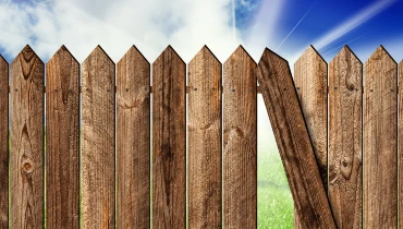 A wooden fence with a crooked picket that should be fixed with professional service for fence repairs.