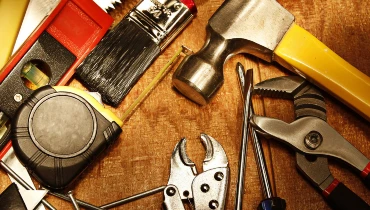 An assortment of different hand tools used for home improvement projects, including a hammer, tape measure, pliers, screwdrivers, and a level.