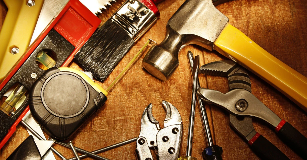 An assortment of different hand tools used for home improvement projects, including a hammer, tape measure, pliers, screwdrivers, and a level.