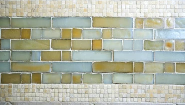 A custom tile backsplash made of several different colors and sizes of glass and ceramic tiles.