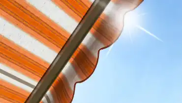 A view of an awning from below as it blocks out the shining sun in the sky above.