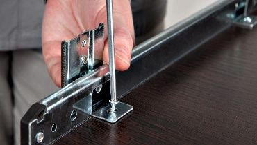 A handyman using a screwdriver to attach the tracks for a drawer during an appointment for furniture assembly in arlington