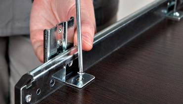 A handyman using a screwdriver to attach the tracks for a drawer during an appointment for furniture assembly in Arlington