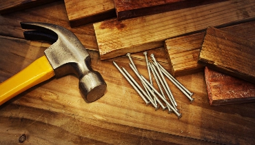 A hammer, nails, and wooden boards used for deck installation projects.
