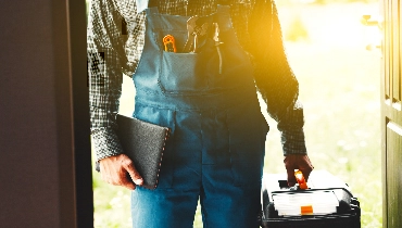 handyman in overalls holding toolbox