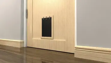 The bottom of a residential door where a large, black dog door has been installed just above the bottom of the door.