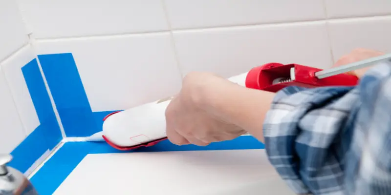 A professional handyman applying grout to bathroom tile.