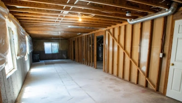 An unfinished basement with exposed frames that has been cleaned and prepped for a basement remodel.