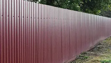 A metal fence running along a property line after fence installation has been completed.