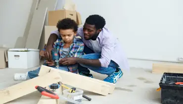 Black father helping son assemble wood