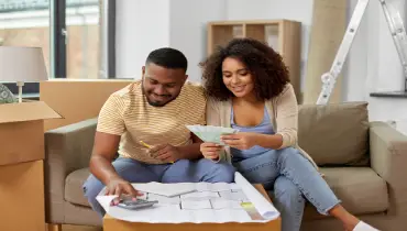 Black couple sitting on couch planning home renovation