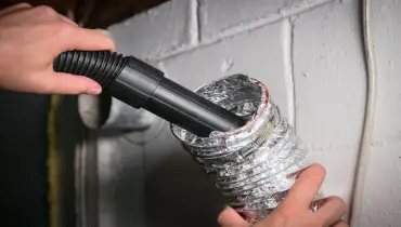 Person cleaning dryer vent hose