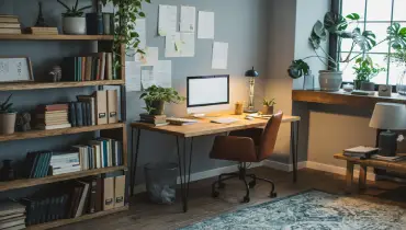 An inviting home office is seen with a desk, computer, and chair featuring plants and other decorations.