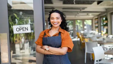 Young business woman wearing apron standing with open sign