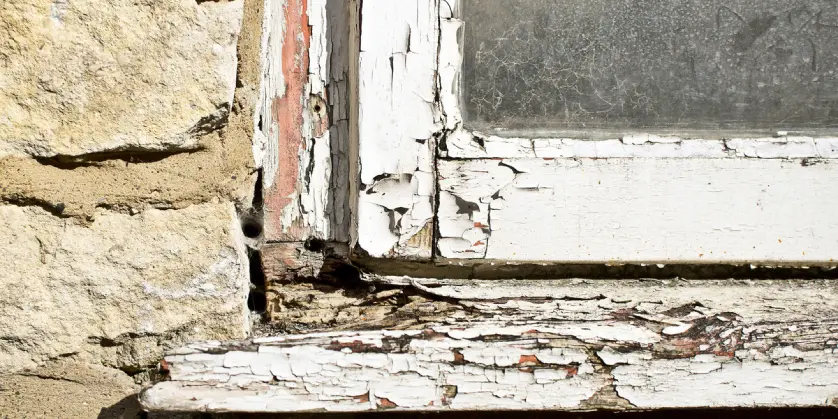 An old window frame in need of trim repair in McKinney, TX for rotted, worn parts of the outer frame.