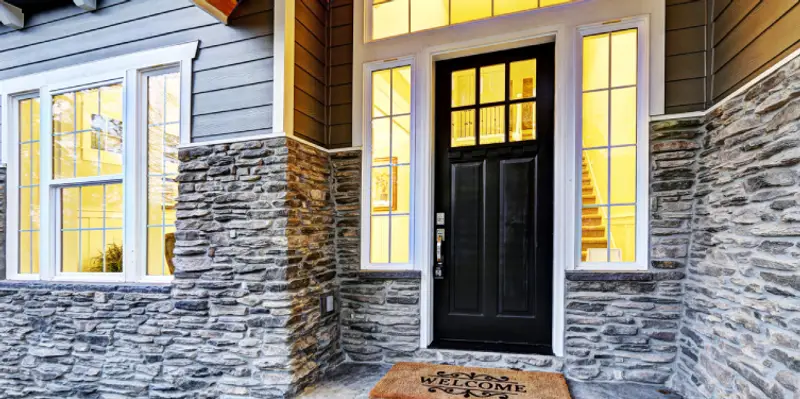 The front porch of a home with visible white trim around the door, windows, and siding, which has been kept in good condition with professional trim repair.