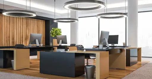 An office with an open floor plan and modern lighting, desks and decor.