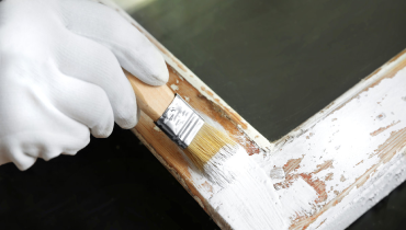 A handyman painting part of a home’s exterior trim during an appointment for trim repair.