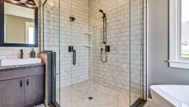 A completed shower remodel for a corner shower with glass walls and stone tile.