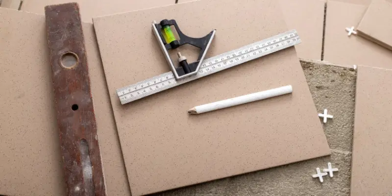 Tools and equipment commonly used for tile repair in Oklahoma City sitting on a tile floor in the process of having a single tile replaced.