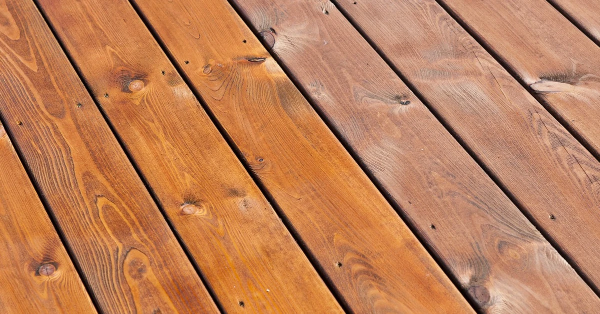 Wooden deck boards on a porch that has been partially refinished after receiving service for deck repairs.