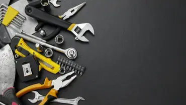 A collection of tools used by general contractors in Charleston, including a socket wrench, adjustable wrench, tape measure, pliers, and putty knife.