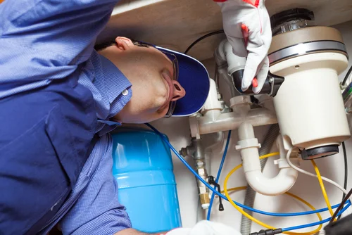 Man repairing a garbage disposal