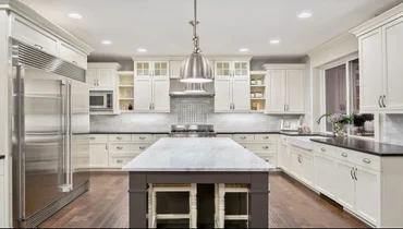 Kitchen with wood floors and white cabinets and marble counter tops