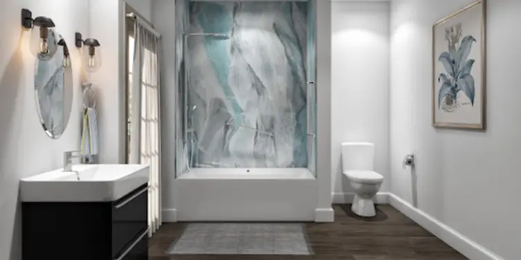 A bright, white bathroom with dark wood flooring and a mosaic design in the wall that wraps around the tub.