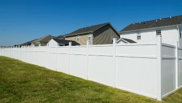 A long white vinyl fence surrounding several residential properties