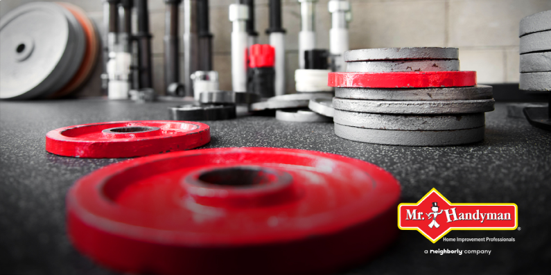 Red and silver gym weights of different sizes on a gym floor.
