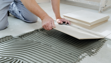 worker laying floor tiles