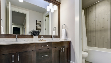 White and brown modern bathroom with double vanity and large mirror.