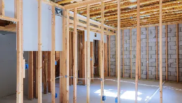 A basement under construction with an unfinished wood frame and a brick wall.