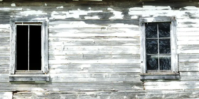 Weathered, worn, white wood siding that needs professional siding repair service.