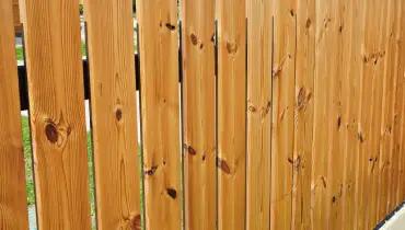 A close-up image of new wooden fence pickets that have been installed during a fence repair project.