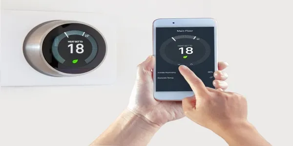 Smart Thermostat with a person using their phone to adjust room temperature.