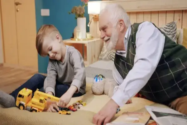 Grandfather and boy spending time together, playing with toy car.
